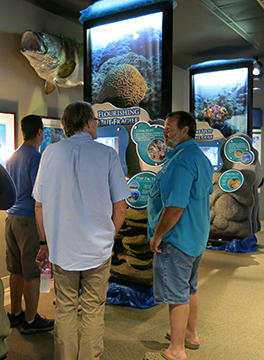 Three men standing in front of the Flourishing but Fragile section of the traveling exhibit.