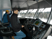 Captain Chuck at the helm of the R/V Manta with 2 people visible in background