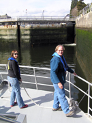 Emma and G.P. manning lines by the front railing of the Manta as the boat approaches the closed gates of the lock