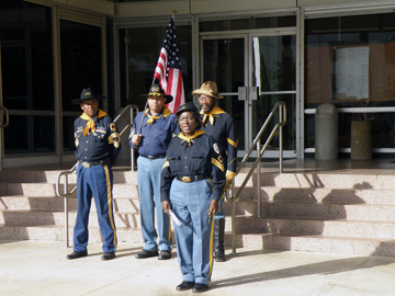 Four Buffalo Soldier re-enactors standing with an American flag in front of courthouse steps