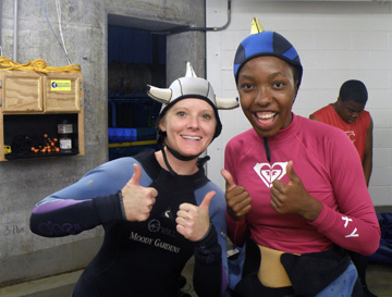 Two divers wearing hoods with shark fins on top. One hood is also shaped like a hammerhead shark.