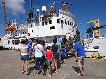 Group of people boarding the ship via a gangway from the dock.