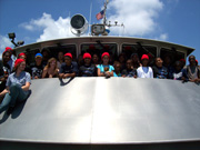 A group of students, several wearing red caps, on board the R/V Manta