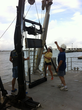 Three people hoisting the MOCNESS sampling equipment onto the boat using the A-frame