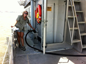 Woman holding fuel hose while fueling a boat