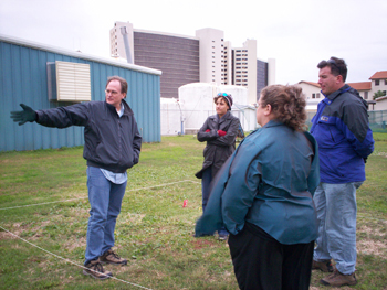 Four sanctuary staff standing in a grassy field discussing boat layout.