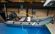 A small rigid hull inflatable boat with an outboard motor sitting on the upper deck of the R/V Manta.