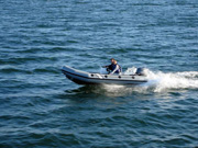 The Manta's inflatable work boat being driven across the water by two people