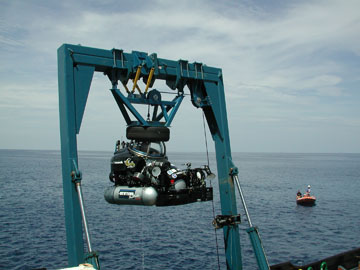 A one-person submersible suspended from a crane.