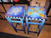 Two wooden stools painted with images of fish from the sanctuary