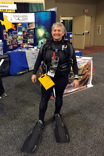 A women dressed in scuba gear standing in front of a Flower Garden Banks display at a science teacher conference