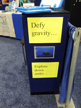 Signs in the NOAA display booth: Defy gravity...Explore down under...