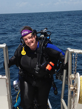 A smiling diver climbing up the ladder onto the boat after a dive.
