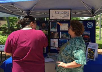 Shelley DuPuy talking to a visitor in front of the sanctuary display booth
