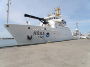 A large white NOAA ship tied up to a pier.