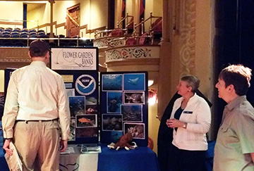 Guests look at a table top display about the sanctuary while Kelly Drinnen stands alongside.