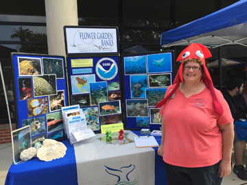 Woman wearing a red squid hat standing in front of a sanctuary display table outside a building