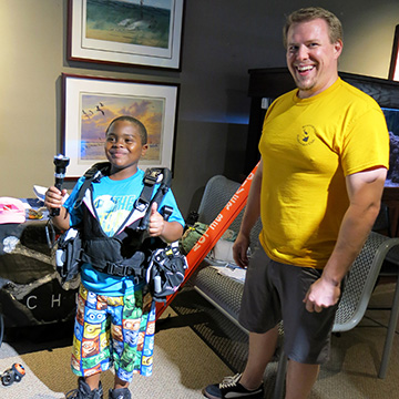 A dive volunteer standing next to a child wearing scuba gear.
