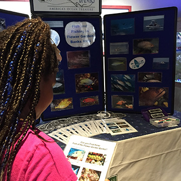 A girl looking at her Fish Scavenger Hunt pictures before heading off to see what she can find.
A sanctuary fishing display is in the background.