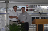 G.P. Shmahl and John Boerstler shake hands as John hands G.P. a certificate of recognition.