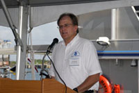 G.P. Schmahl in a white shirt with NOAA logo talks to the guest from the speakers' dais.