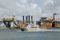 The vessel Manta in the harbor in front of Pier 21.  Small Coast Guard vesel visible to the left.  Oil & gas platform servicing facilities in the background.