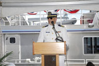 A Navy chaplain in dress white uniform offers an invocation from the speakers' dais.