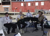 A five-piece brass band and drummer play the national anthem.  Two of the band members are out of the picture to the right.