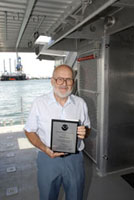 Dick Zingula standing on the back deck of the Manta holding his award plaque.