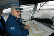 Dan leaning on a navigation chart at the chart table in the pilot house