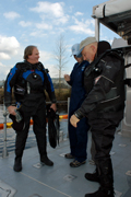 G.P. in his dry suit standing to the left of Mitchell and Dan on the main deck.  Dan is also in a dry suit.  Mitchell, in the middle, is ina NOAA jumpsuit and a ball cap.