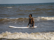 Basir in the water with a surfboard floating alongside him.
