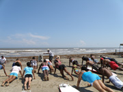 Leader directs students on beach to do pushups.