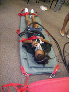 A student lying down and strapped in to a soft mat.