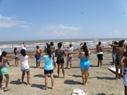 Students lined up on the beach and stretching their arms.