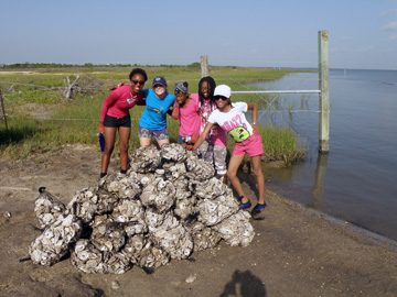 Students gathered around a pile of oyster shell sacks they just unloaded by the water.