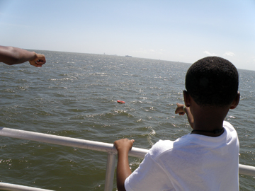 Student pointing at floating lifesaving ring behind the boat.