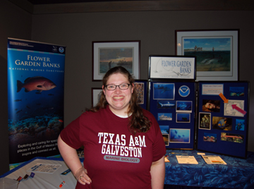 Andrea, a sanctuary volunteer, standing in front of the display proudly wearing her Texas A&M Galveston Marine Biology shirt