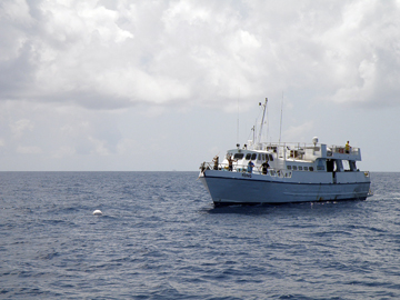 A 100-foot dive vessel tied to a mooring on the sea surface.