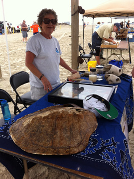 A woman standing behind a table holding sea turtle artifacts