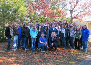 Group of meeting participants in winter clothing gathered under some trees at the zoo.