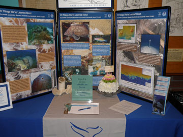 Table top display about Flower Garden Banks National Marine Sanctuary with a cake-shaped flower arrangement in front of it.