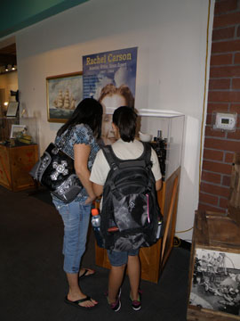 Two guests looking at a display case next to a banner about Rachel Carson.