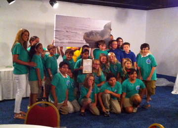 Group of students and a teacher posing with a large image of a Kemp's Ridley sea turtle