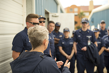 Looking from behind Kelly Drinnen at a group of Coast Guard staff in uniform as Kelly explains what they are about to see in the turtle barn.