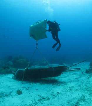 A diver filling a lift bag being used to lift heavy debris off the seafloor.