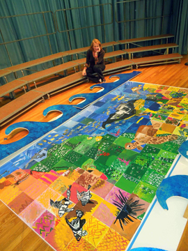 Artist Jacqui Stanley squats near the mural of the Flower Garden Banks created by students at Oppe Elementary School