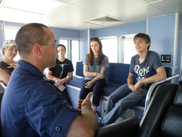 Several students talking to NOAA Corps officer on boat