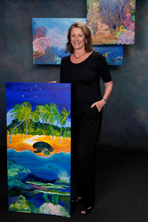 Woman standing amid three of her paintings