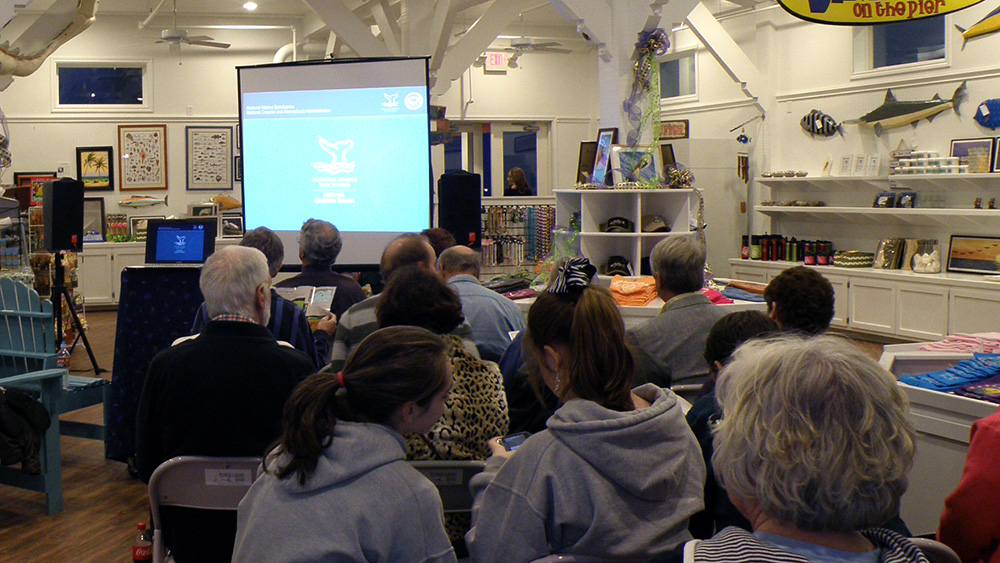 People sitting in front of a screen showing a presentation about the sanctuary